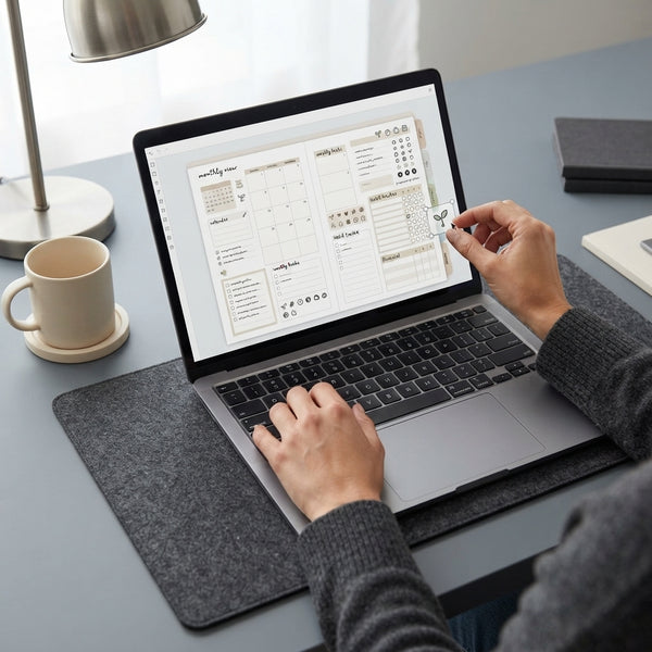 Hands editing digital planner elements on a laptop screen in a clean, professional workspace with neutral decor.